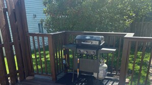 A barbecue grill on a wooden deck with a metal railing. - Cozy, spacious house located near historic downtown near shopping and dining. (Watertown)
