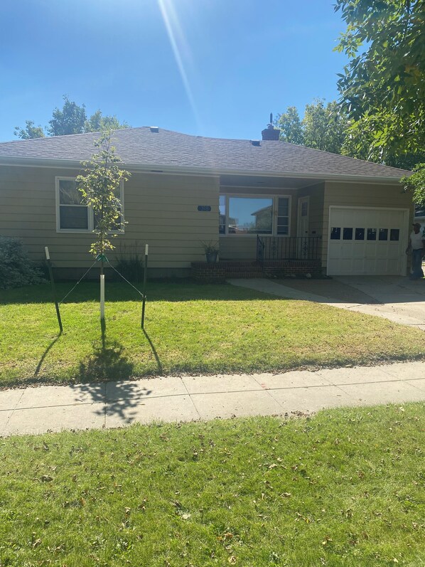 A single-story house with a garage, a small porch, and a lawn. - Cozy, spacious house located near historic downtown near shopping and dining. (Watertown)