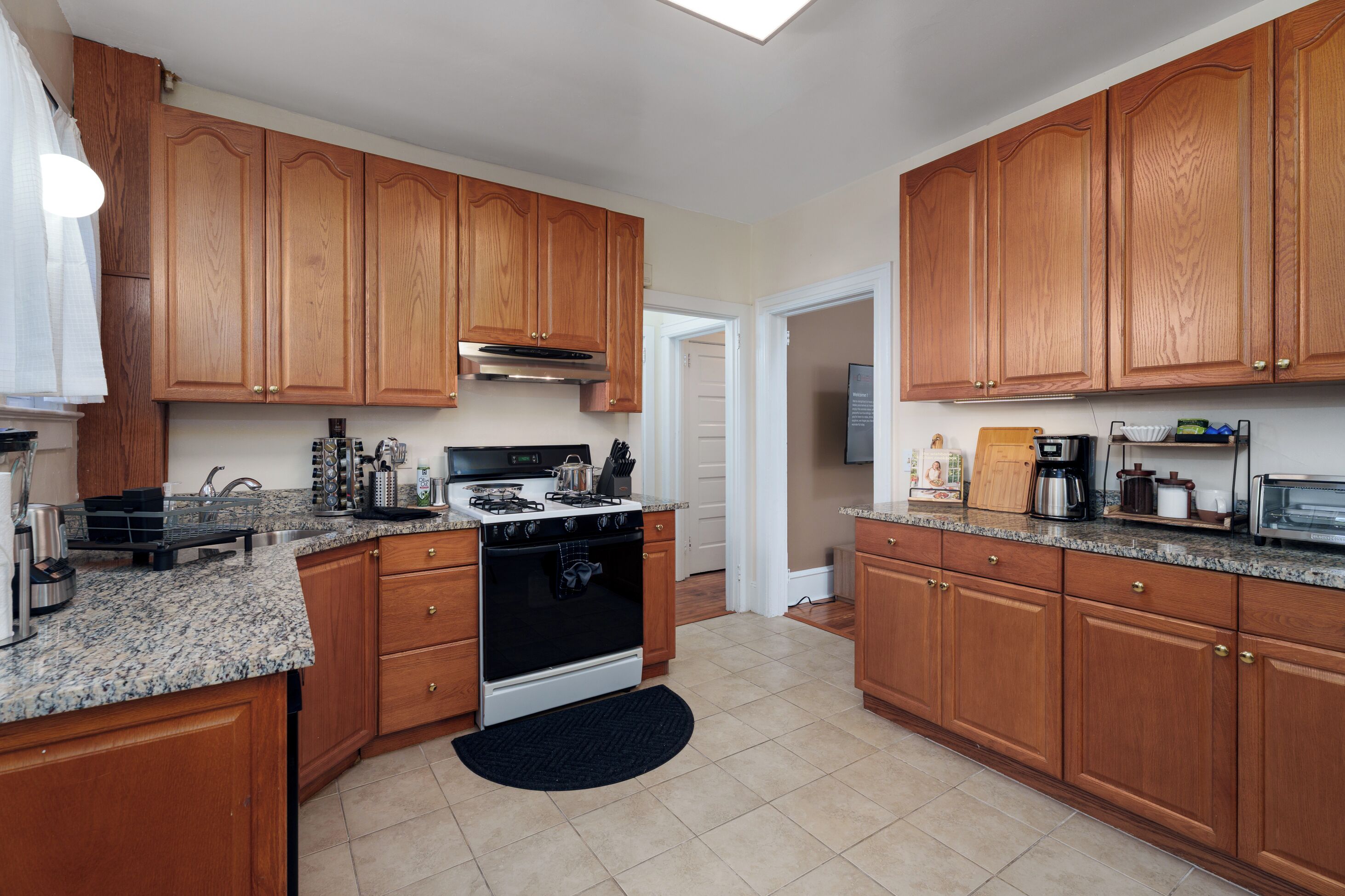 A kitchen with wooden cabinets, granite countertops, a stove, and a microwave.
