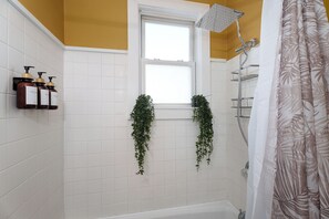 Un bagno con finestra, doccia e articoli da toilette a parete.
