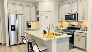 A modern kitchen with stainless steel appliances, a central island with bar stools, and a microwave above the stove. - Luxe Retreat - 8 Guests - Off I-70-E-470 - Anschutz Medical - Trails - Airport (Aurora)