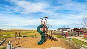 A playground with a slide and climbing structures, surrounded by a park with benches and a building in the background. - Luxe Retreat - 8 Guests - Off I-70-E-470 - Anschutz Medical - Trails - Airport (Aurora)