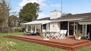 Une maison moderne dotée d’un patio aménagé avec des meubles d’extérieur et un espace salon abrité.
