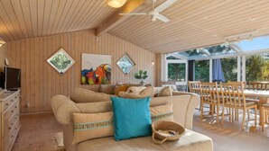 A cozy living room with a sofa, a TV, and a dining area with chairs and a table. - 5 Star Holiday Home in Saeby (Ronde)