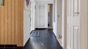 A hallway with a black tiled floor, a welcome mat, and a door with a metal gate. - 5 Star Holiday Home in Saeby (Ronde)