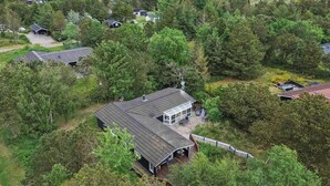 A coastal property with multiple houses surrounded by dense forest, a beach in the background, and a clear view of the ocean. - 5 Star Holiday Home in Saeby (Ronde)
