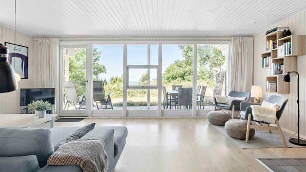 Ein modernes Wohnzimmer mit einem großen Schiebeglasfenster, das auf eine Außenpatio führt.
