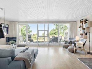 A modern living room with a large sliding glass door leading to an outdoor patio area. - 5 Star Holiday Home in Hasle (Hasle)