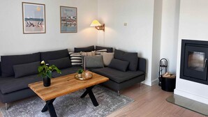 Ein modernes Wohnzimmer mit grauem Sofa, einem Holztisch und zwei Wandleuchten.