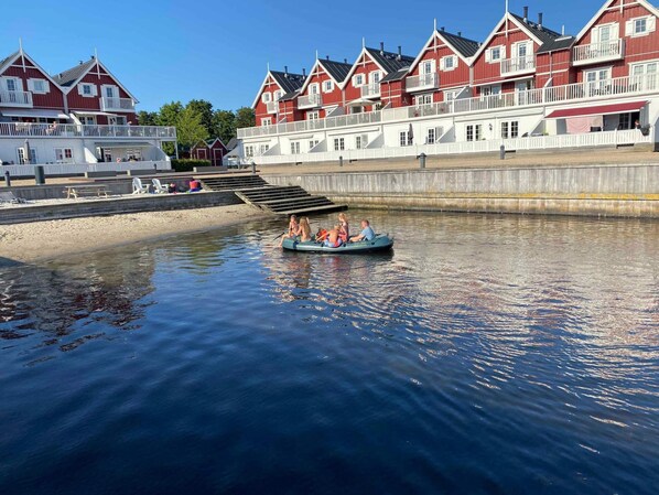 A canal with a rowboat carrying passengers, surrounded by red buildings with white balconies.