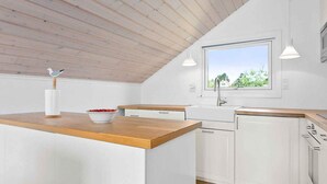 A modern kitchen with white cabinets, a wooden countertop, a window with a view, and pendant lights. - 5 Star Holiday Home in Ebeltoft (Ebeltoft)
