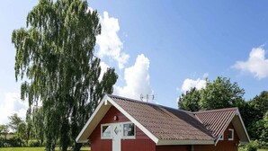 A small, single-story red building with a sloped roof, a front door, and a small porch. - 5 Star Holiday Home in Ebeltoft (Ebeltoft)