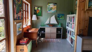 A cozy room with wooden walls, a desk with a lamp, a bookshelf, and a sailboat model. - 4 Star Holiday Home in Kirke Hyllinge (Kirke Hyllinge)