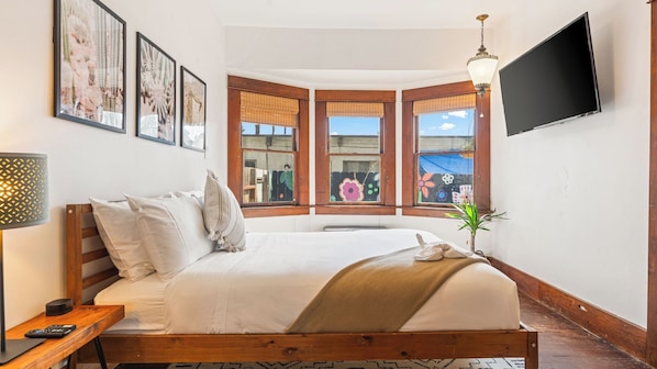 A bedroom with a bed, a TV, a lamp, and a window with a view.