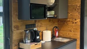 Een kleine keuken met een magnetron, koffiezetapparaat en spoelbak.