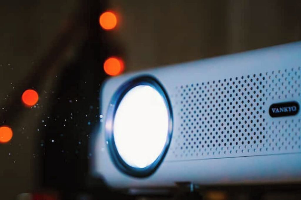 A projector with a bright lens and a perforated speaker grille, labeled "VANKYO."