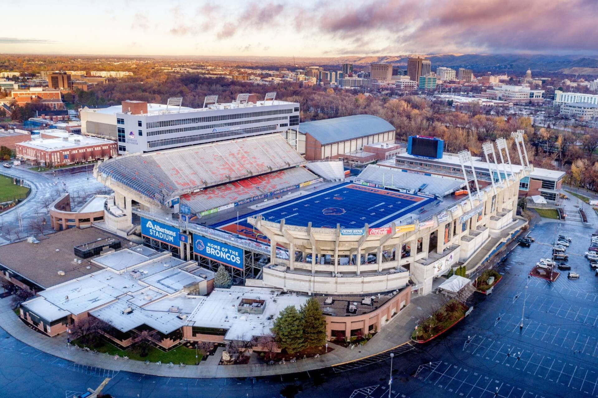 Vue aérienne d’un stade avec un grand terrain, des bâtiments environnants et un parking.