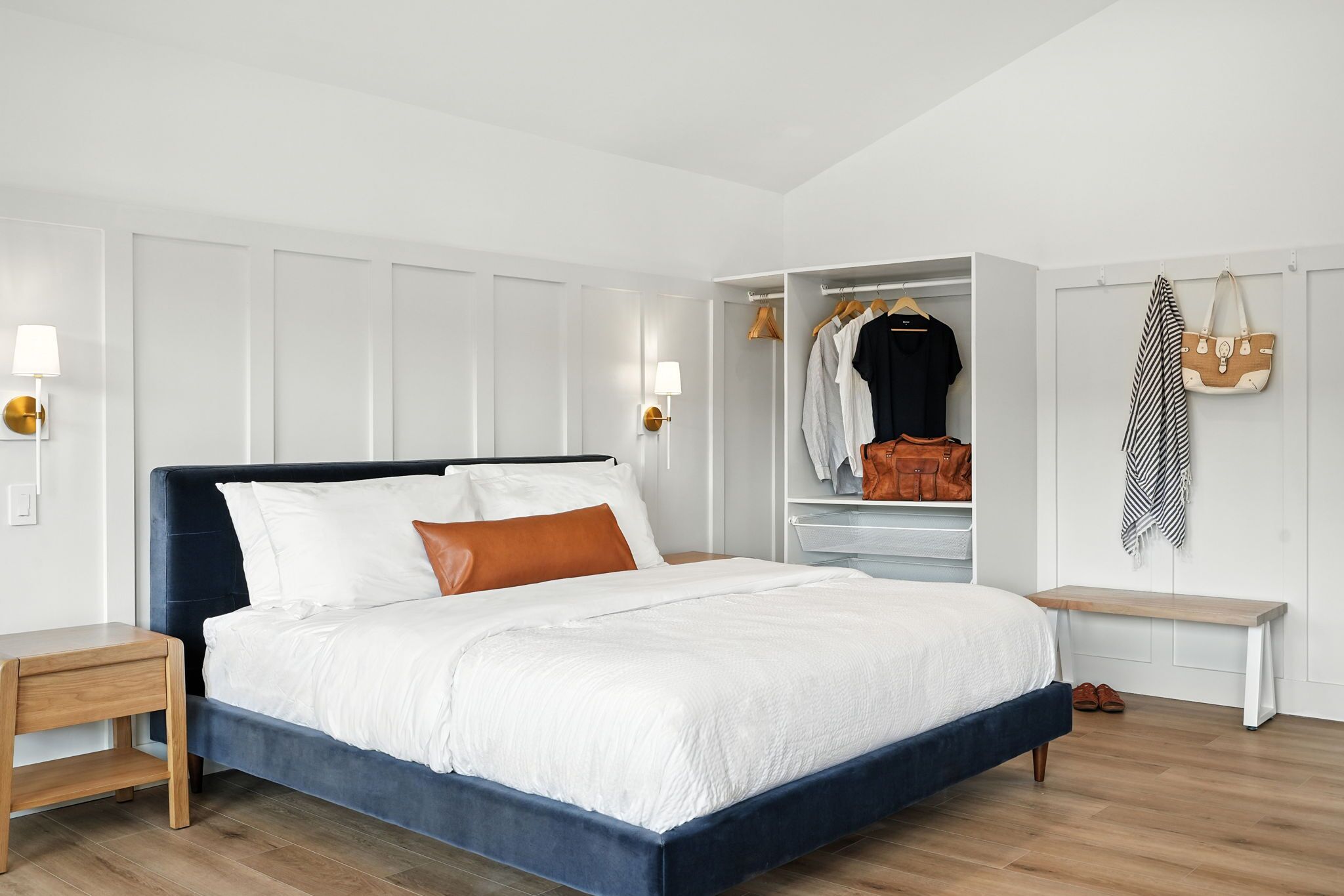 A bedroom with a bed, bedside table, wardrobe, and a bench.