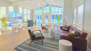 A spacious living area with a large window, a brown leather sofa, and a dining table with chairs. - Lakelyn Lodge (Lakeville)