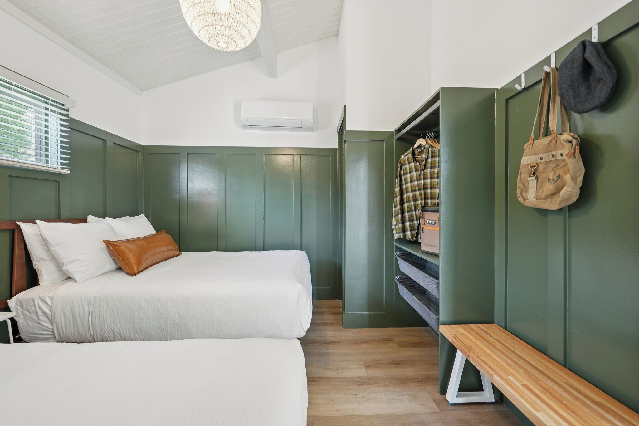A bedroom with a bed, a bench, a wardrobe, and a hanging bag.