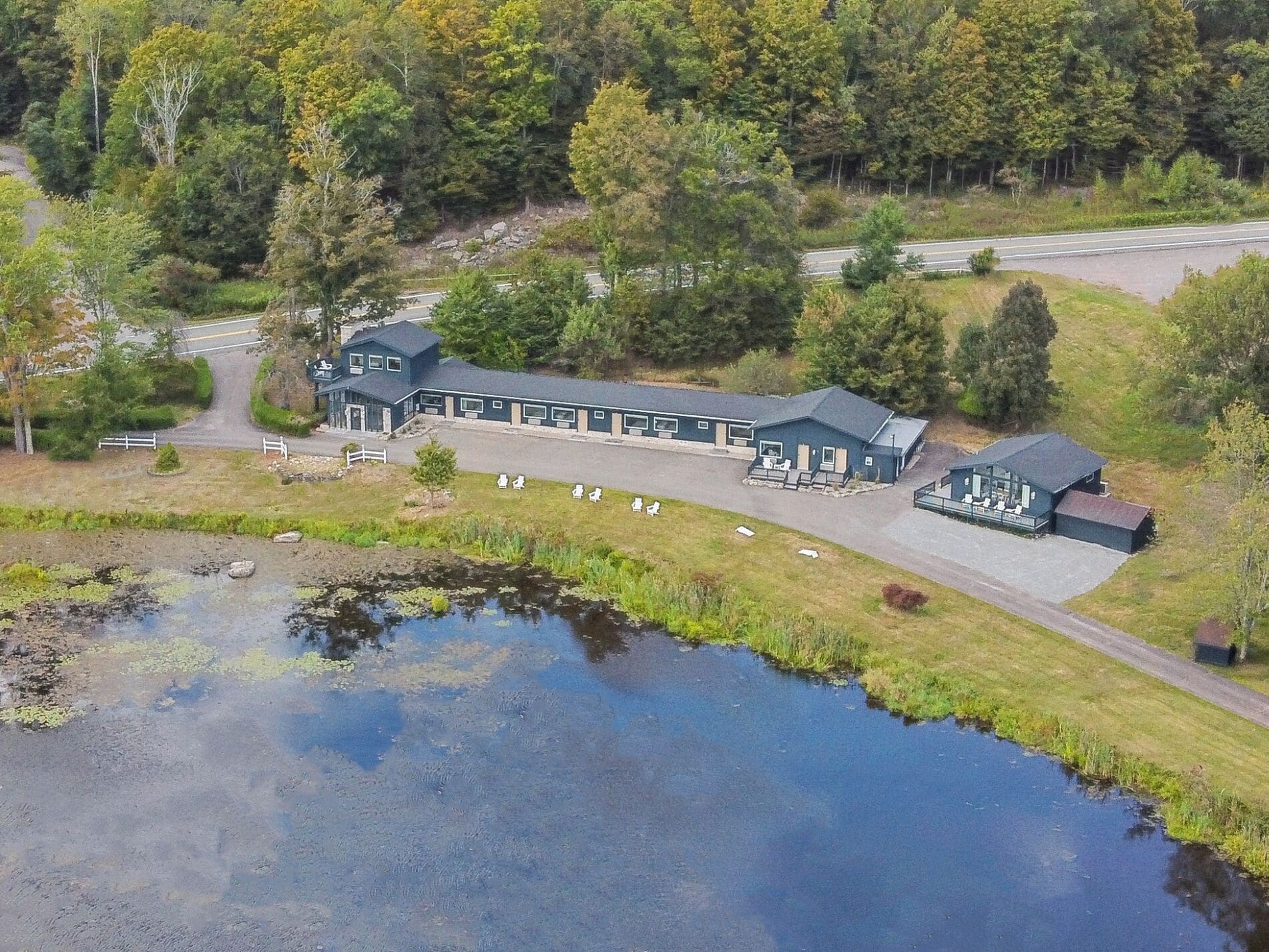 A lodge with a large building, a covered patio, and a pond.