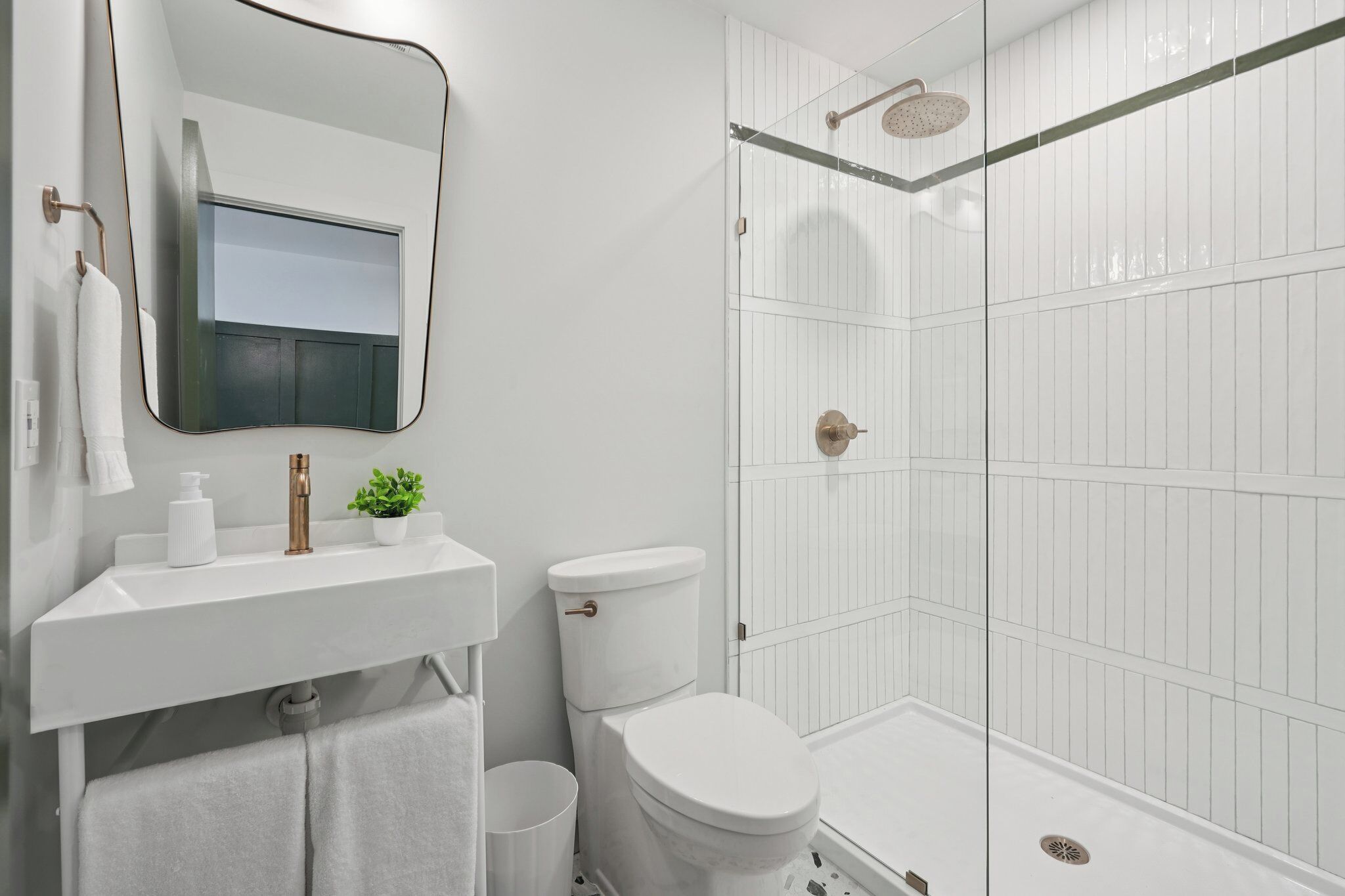 A modern bathroom with a white sink, toilet, and shower.
