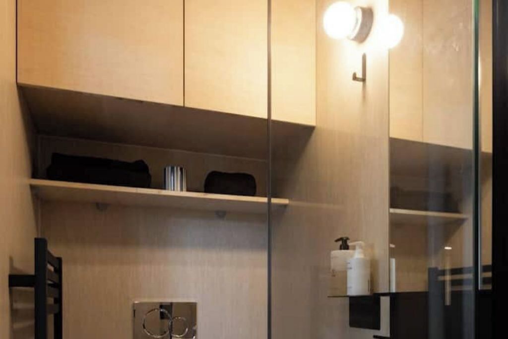 Un bagno moderno con box doccia in vetro, un porta asciugamani e uno scaffale con articoli da toilette.