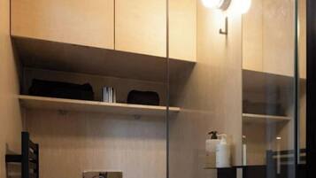 Un bagno moderno con box doccia in vetro, un porta asciugamani e uno scaffale con articoli da toilette.