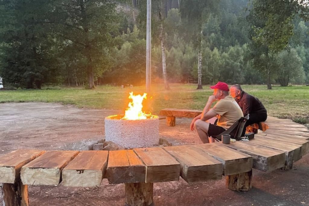Un banc circulaire en bois, disposé en cercle, avec un foyer au centre.