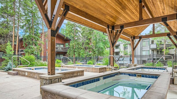 A covered outdoor swimming pool area with multiple hot tubs, wooden beams, and a stone border. -   UPDATED CONDO 5 MIN WALK TO QUICKSILVER LIFT & MAIN ST HOTUBS-POOL-NEW FURN! (Breckenridge)