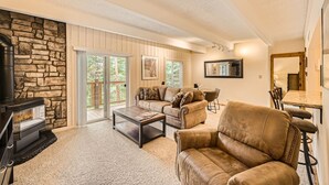 A cozy living room with a stone fireplace, leather furniture, and a dining area. -   UPDATED CONDO 5 MIN WALK TO QUICKSILVER LIFT & MAIN ST HOTUBS-POOL-NEW FURN! (Breckenridge)