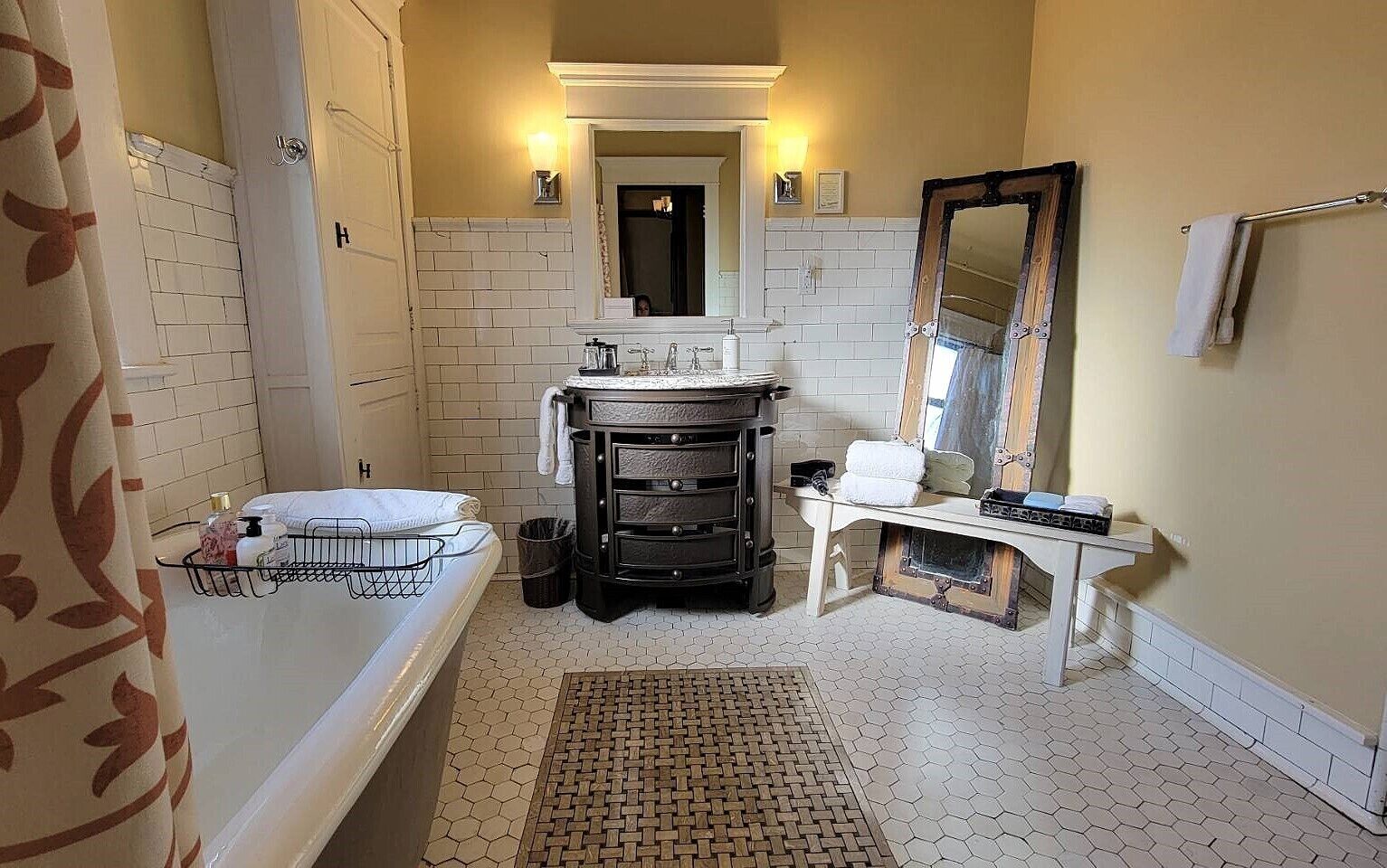A bathroom with a bathtub, a sink, a mirror, and a vanity with drawers.