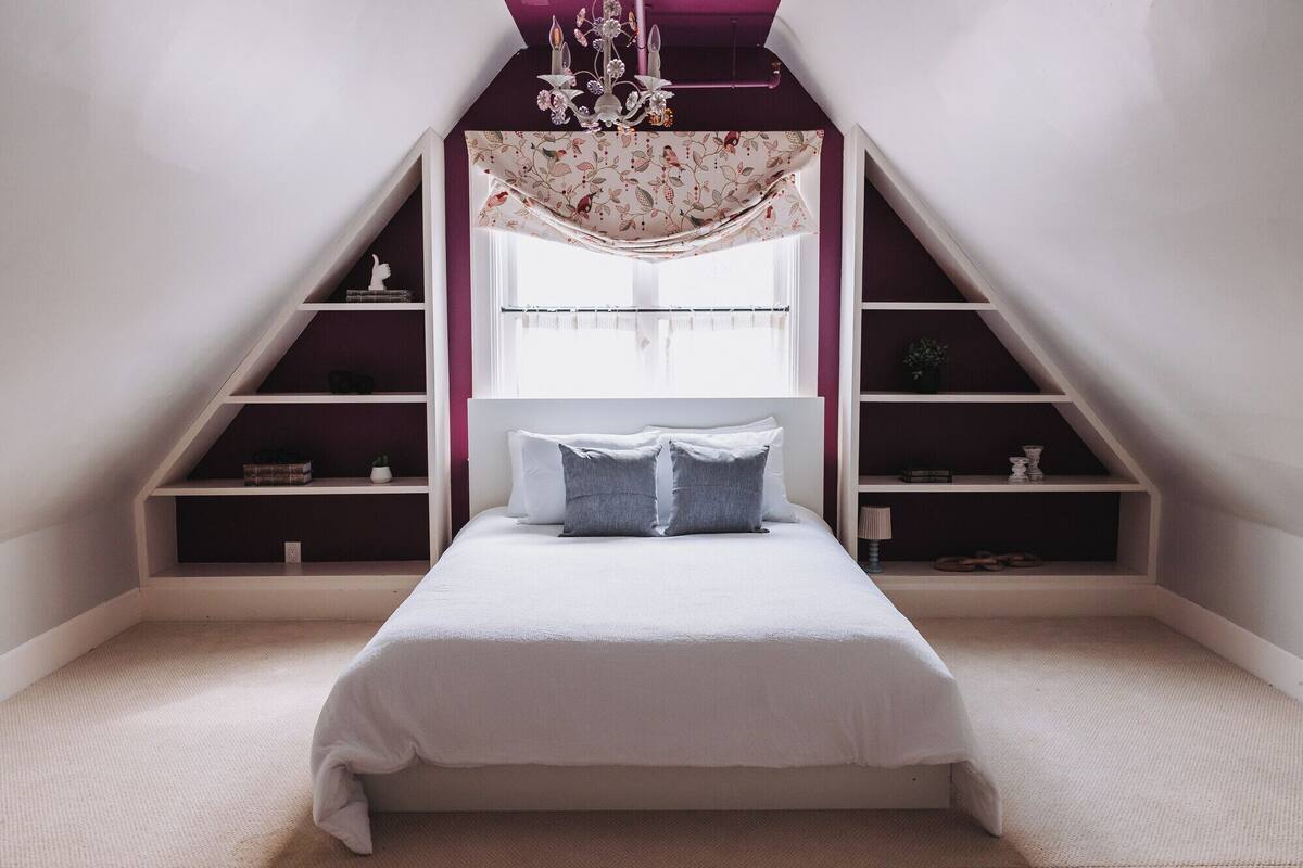 Une chambre à coucher avec un lit, un lustre et des étagères intégrées.