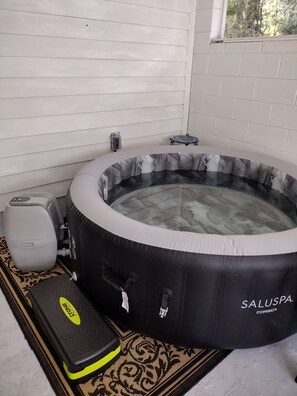A hot tub with a marble interior, a step for entry, and a control panel.