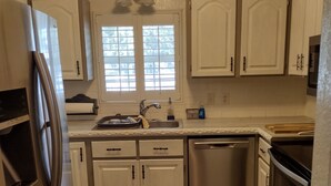 A modern kitchen with white cabinets, stainless steel appliances, and a wooden floor. - Charming 2-bedroom, 1 bath, game room, patio fenced.in lovely Ocala (Ocala)