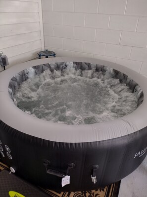 A hot tub with a black exterior and a white interior, surrounded by a tiled wall.