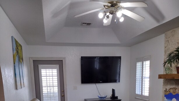 A living room with a ceiling fan, a flat-screen TV, a reclining chair, and a wooden floor. - Charming 2-bedroom, 1 bath, game room, patio fenced.in lovely Ocala (Ocala)