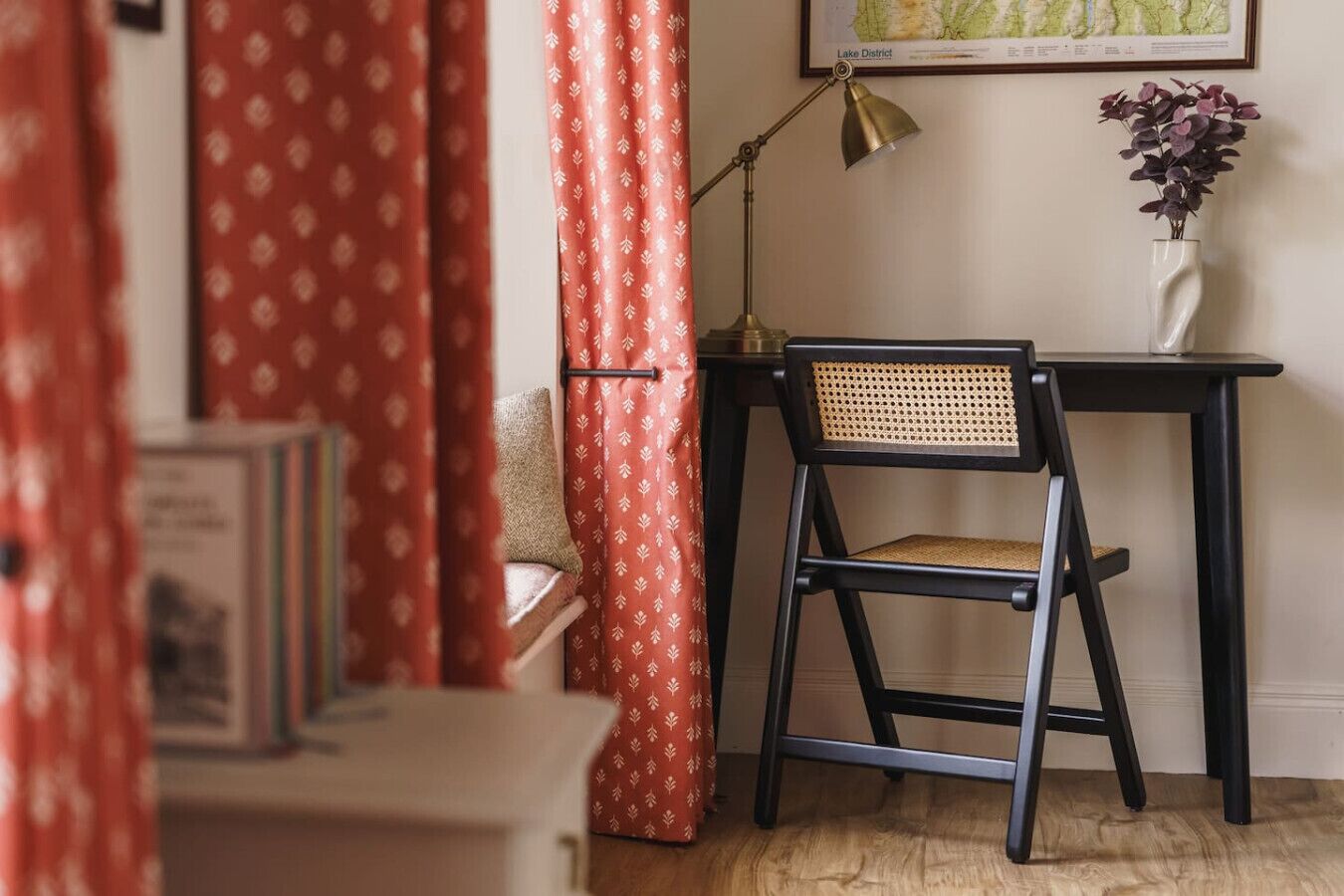 A room with a desk, chair, lamp, and a map on the wall.