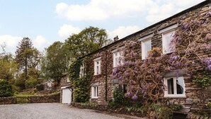 A stone building with multiple windows, a gravel driveway, and surrounding greenery. - 2 Hart Head Barn, Beautiful Renovated Barn in Rydal Sleeping 10. (Ambleside)