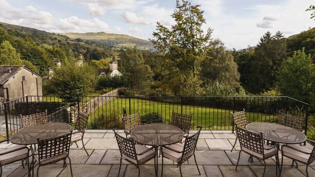 A patio with round tables and chairs, overlooking a lush valley with hills and trees. - 2 Hart Head Barn, Beautiful Renovated Barn in Rydal Sleeping 10. (Ambleside)