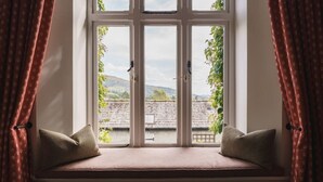 A window seat with two cushions, a view of a building and greenery outside. - 2 Hart Head Barn, Beautiful Renovated Barn in Rydal Sleeping 10. (Ambleside)
