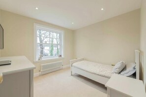Une chambre avec un lit simple, un bureau et un radiateur.
