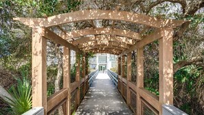 Un pont piétonnier en bois, doté d’une passerelle couverte, entouré de verdure et d’arbres.