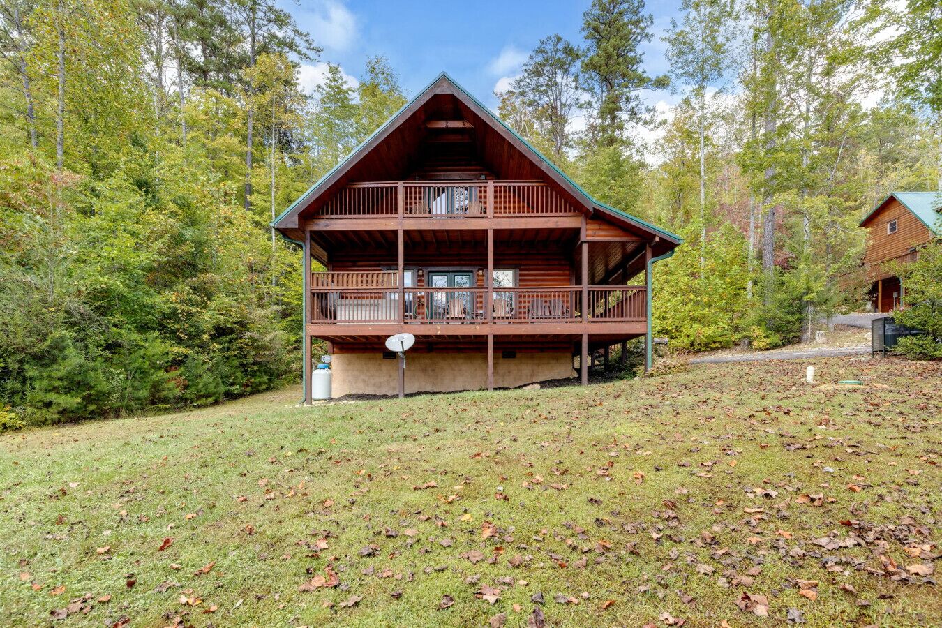 Eine zweigeschossige Blockhütte mit Balkon, umgeben von einem bewaldeten Gebiet.