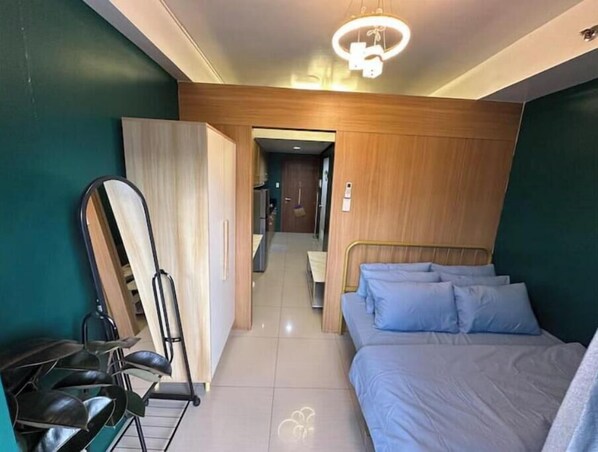 A bedroom with a bed, a wardrobe, and a mirror.