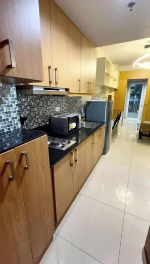 Una cocina moderna con armarios de madera, encimera negra y salpicadero de azulejos.