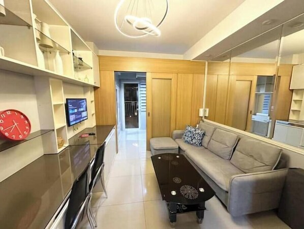 Una sala de estar moderna con un sofá, una mesa de centro, un televisor y un reloj rojo.
