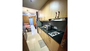 A compact kitchen with wooden cabinets, a black countertop, and a toaster. - Kathy’s Crib Family Suite Room at Shell Residence (Pasay City)