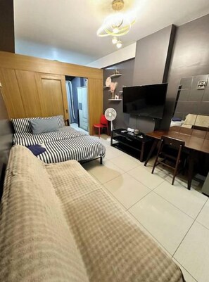 A modern hotel room with a bed, a TV, a desk, and a chair.