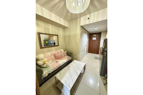 Una habitación de hotel con sofá cama, una mesita de centro de mármol, un espejo y una araña.